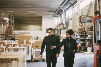 Female entrepreneur pointing while discussing with male colleague at distribution warehouse