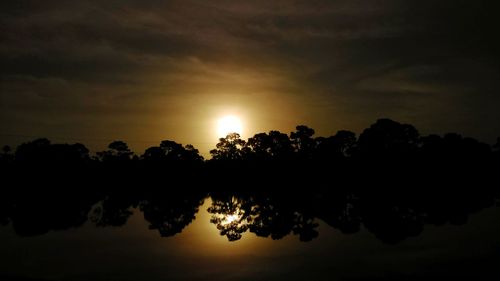 Silhouette of trees against cloudy sky