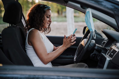 Side view of woman using mobile phone in car