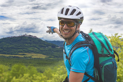 Portrait of happy mountain biker pointing at mountain