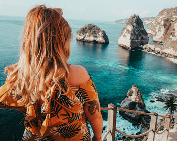 Rear view of woman with tattoo looking at sea