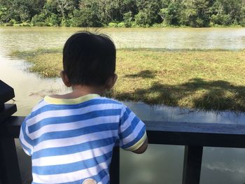 Rear view of boy standing by river