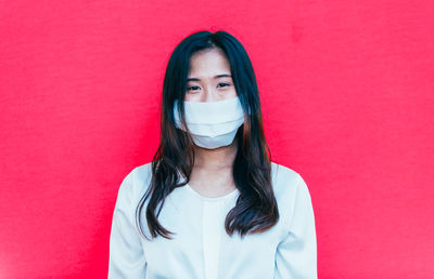 Portrait of beautiful young woman against pink wall