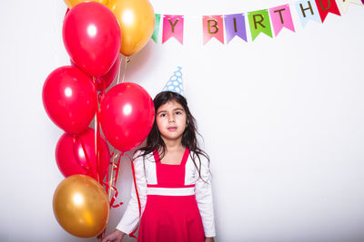 Full length of woman with balloons standing against wall
