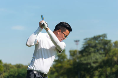 Rear view of man playing at golf course