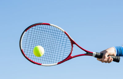 Low angle view of hand holding ball against clear sky