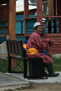 Side view of man sitting on bench