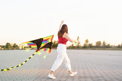 Rear view of woman with umbrella against sky