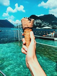 Close-up of hand holding ice cream against sea