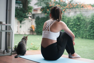 Rear view of woman with cat sitting outdoors