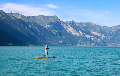 Man in a blue lake against mountains