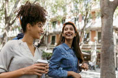 Smiling young woman using smart phone in city