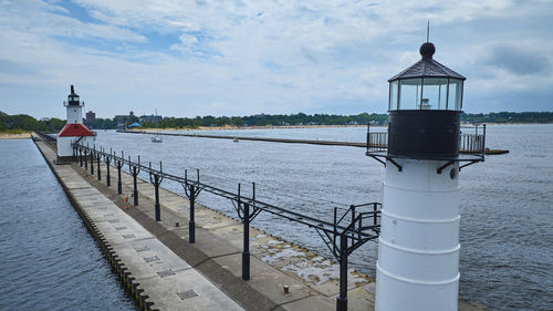 Lighthouse by sea against sky