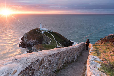 High angle view of lighthouse amidst sea against cloudy sky during sunset