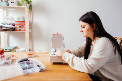 Side view of young woman holding table at home