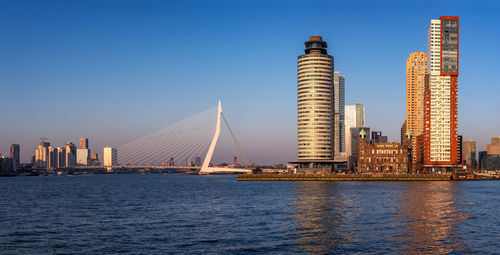 Sea by modern buildings against clear blue sky