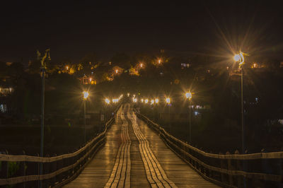 Illuminated footbridge against sky at night