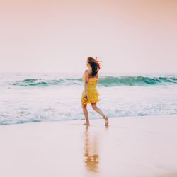 Full length of young woman jumping at beach