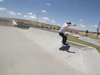 Full length of man skateboarding at skateboard park against sky