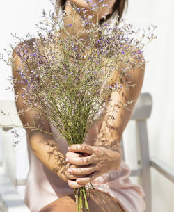 Midsection of woman holding flowering plant