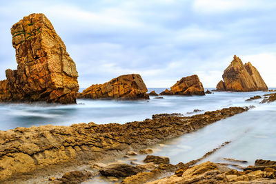 Panoramic view of rocks on beach against sky