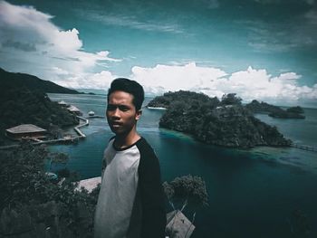 Portrait of young man standing in sea against sky