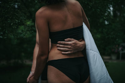 Rear view of shirtless man touching woman
