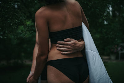 Rear view of shirtless man touching woman