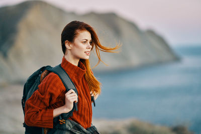 Young woman looking away while standing outdoors