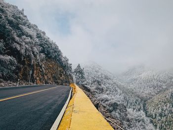 Road by mountains against sky