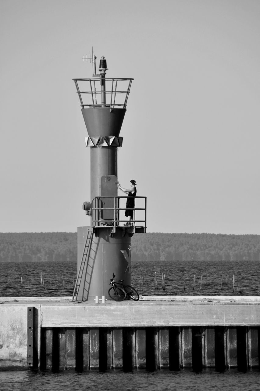 tower, water, black and white, sea, lighthouse, sky, monochrome, monochrome photography, nature, architecture, built structure, black, white, pier, clear sky, day, beach, coast, horizon over water, horizon, protection, security, no people, land, ocean, outdoors, guidance, wood, building exterior, railing