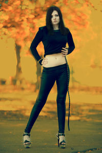 Portrait of young woman standing against orange sky