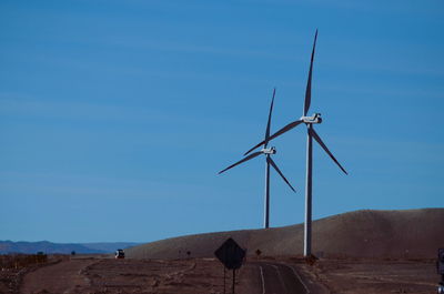 Wind turbines on desert against clear blue sky
