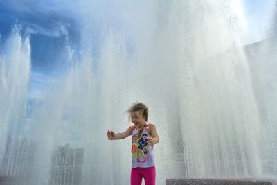 Happy girl standing against fountain 