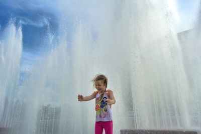 Full length of woman standing against waterfall