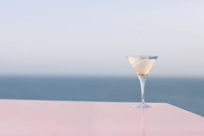 Close-up of wineglass against sea against sky