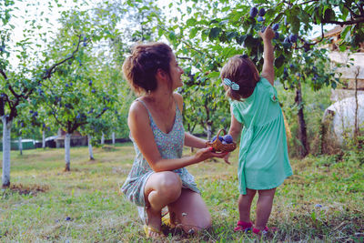 Girl and woman standing by plants against trees