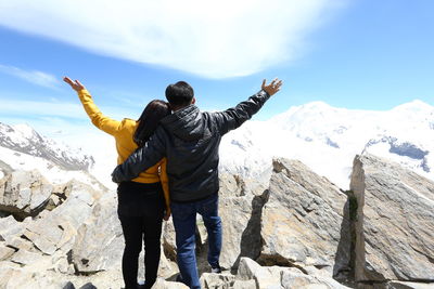 Rear view of people standing on snow covered mountain