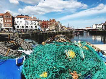 Fishing net on harbor by river against sky