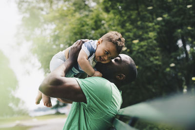 Father kissing happy son while carrying at park