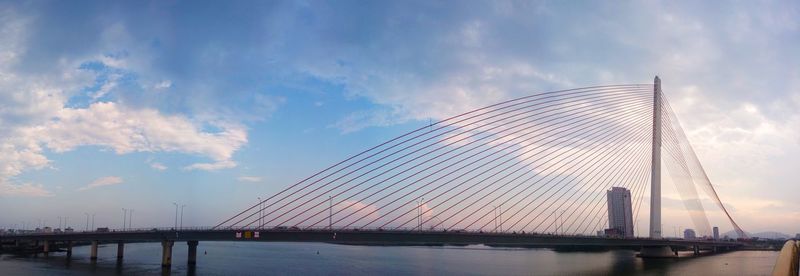 Suspension bridge over river against sky