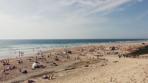 Crowd at beach against sky