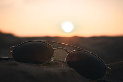 Close-up of sunglasses on street during sunset