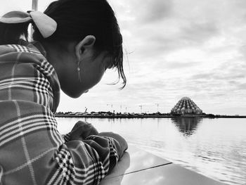 Portrait of woman sitting by sea against sky