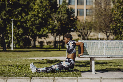 Side view of boy sitting on bench in park