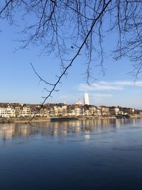 View of buildings by river against sky in city