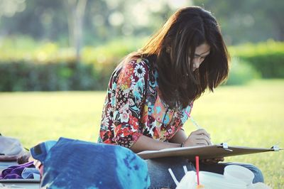 Young woman drawing while sitting at park