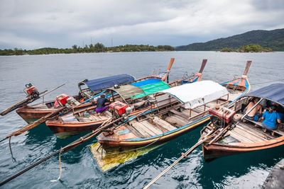 Boats moored at harbor against sky