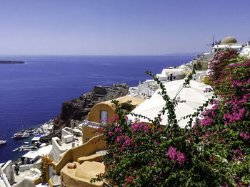 High angle view of townscape by sea against clear blue sky