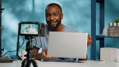 Happy man filming with camera at home